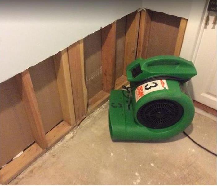 SERVPRO restoration equipment being used in corner of room; flood cuts along wall